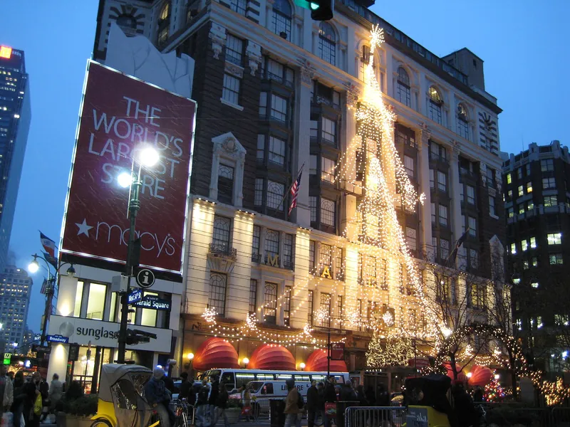 Macy's Herald Square facade strung with holiday lights at dusk